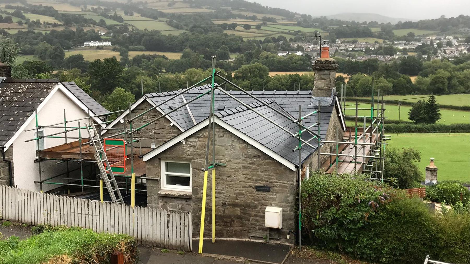 A slate roof being re-laid on a cottage above Crickhowell, with the Usk valley behind