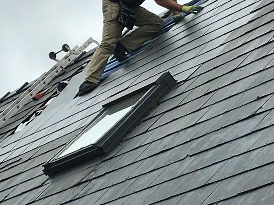 A roofer laying natural slate on a pitched roof