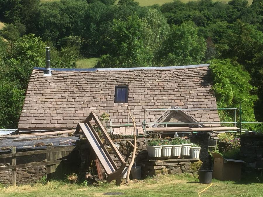 A scaffolded stone barn with the roof stripped back