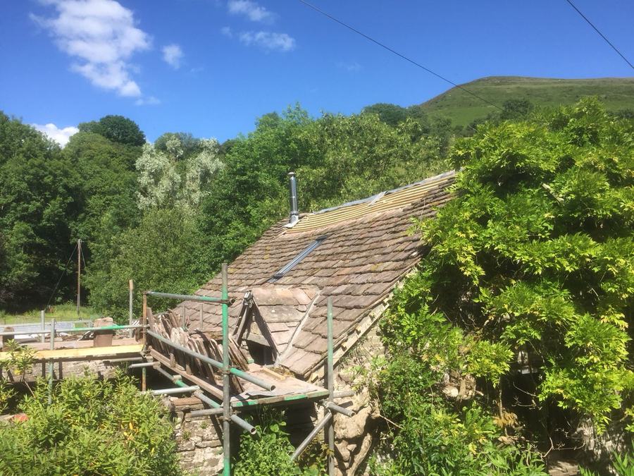 A scaffolded cottage roof being stripped