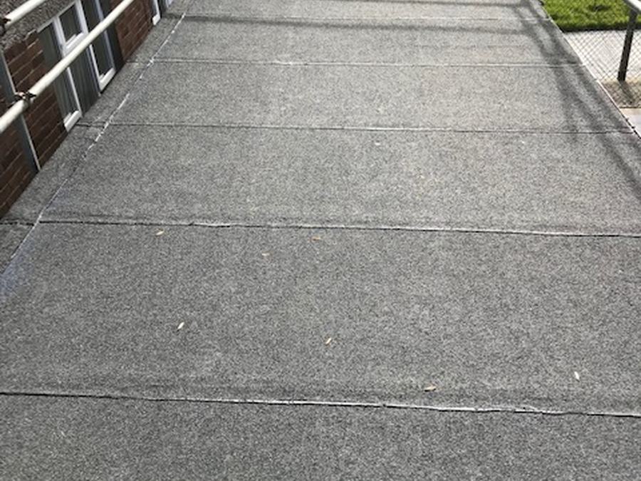 A felt flat roof walkway with handrail
