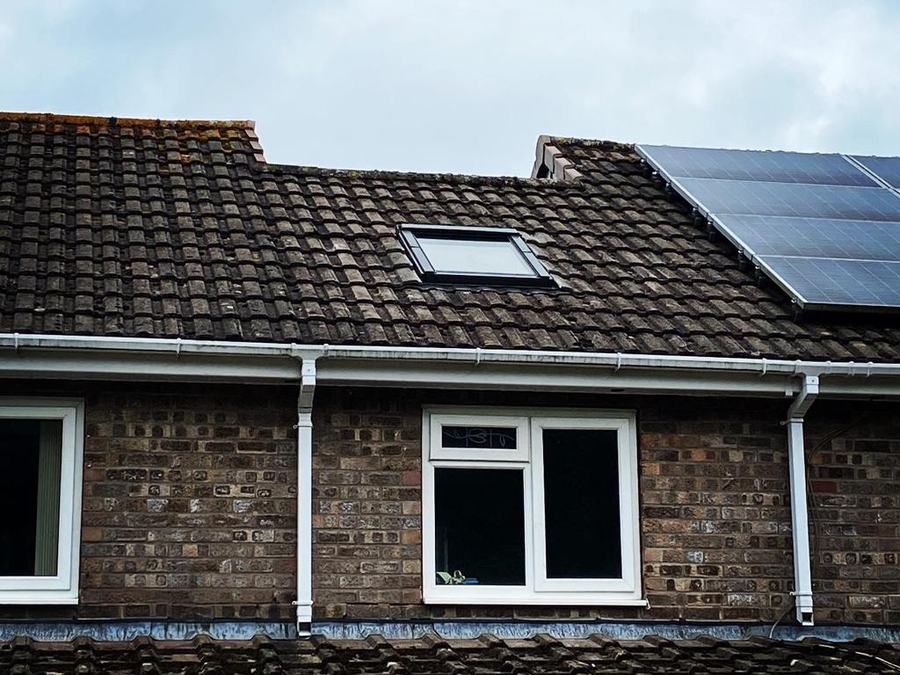 A tiled roof with roof windows and solar panels
