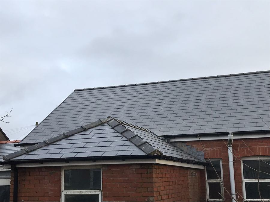 A finished slate roof on a brick house
